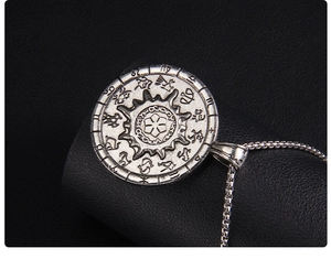 Macro shot of vintage silver zodiac compass necklace with detailed astrological engravings