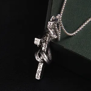 Side view of punk snake coiled around cross necklace in silver stainless steel