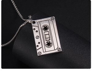 Vue macro d'un pendentif cassette argentée vintage sur un support en cuir noir