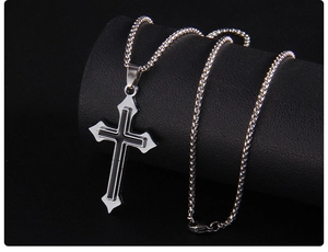 Détail d'un pendentif croix argentée avec émail noir sur un support texturé