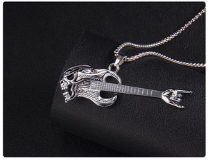 Macro shot of vintage silver guitar skull pendant with rock gesture on leather background