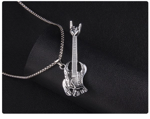 Detail of silver skull guitar pendant with rock hand gesture on black leather display