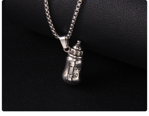 Détail du pendentif biberon argenté avec échelle gravée sur une chaîne à mailles box