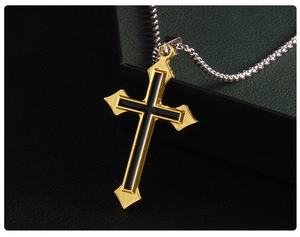 Vue macro d'un pendentif croix vintage plaqué or avec émail noir et une chaîne à mailles carrées