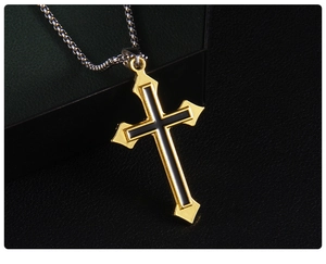 Gros plan d'un pendentif croix géométrique noir et doré sur une chaîne en métal