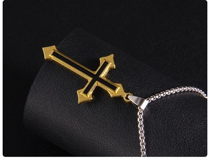 Gros plan détaillé du pendentif croix noir et or avec une chaîne à mailles carrées