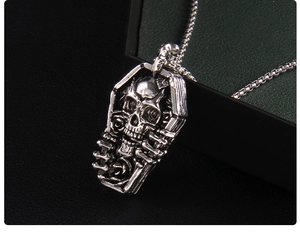 Gros plan du pendentif cercueil gothique avec tête de mort et rose sur chaîne argent
