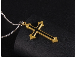 Macro d'un pendentif croix bicolore or et noir sur une chaîne à mailles argentée