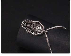 Détail du pendentif cercueil gothique avec crâne sculpté sur une chaîne argentée