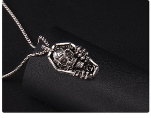 Vue macro du pendentif cercueil punk avec crâne et roses sur un fond en cuir noir