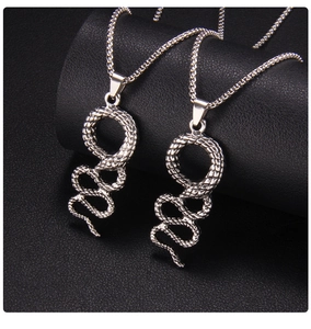Close-up of silver snake pendants with textured scales on black leather roll