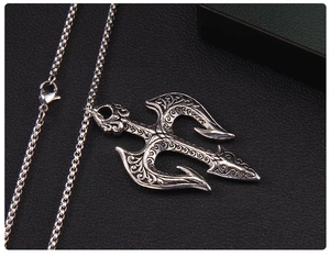 Gros plan détaillé du pendentif trident vintage avec relief baroque sur fond noir mat