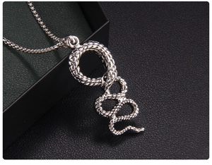 Detailed macro view of a silver snake pendant with intricate scales on a box chain