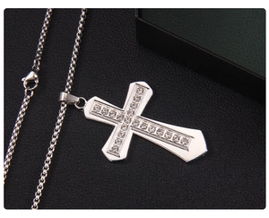 Macro shot of silver stainless steel cross pendant with white rhinestones on black leather