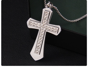 Close-up of a silver cross pendant inlaid with rhinestones on a black leather jewelry box