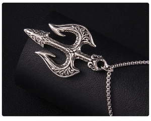 Gros plan du pendentif trident en argent avec gravures vintage sur un support noir élégant