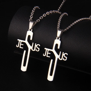 Detailed close-up of two silver stainless steel Jesus cross necklaces on black display stand
