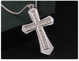 Macro detail of silver cross pendant with sparkling zircons on a black leather display
