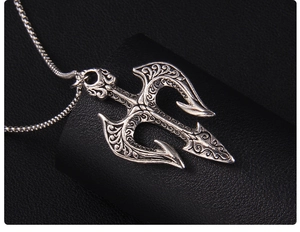Vue macro d'un pendentif trident vintage en acier inoxydable avec gravures gothiques