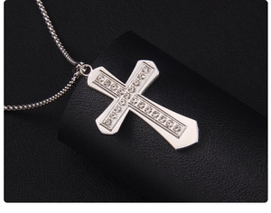 Detailed close-up of a silver cross pendant with sparkling rhinestones on black leather display
