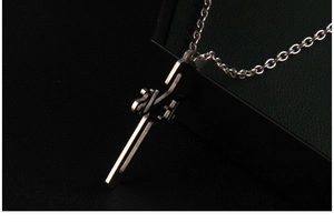 Close-up of industrial style JESUS cross pendant in polished stainless steel finish