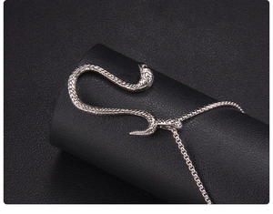 Close-up of silver snake pendant showing detailed scale texture on a black leather stand
