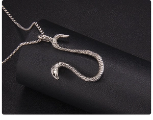 Macro shot of silver snake pendant showing detailed scale texture on black leather