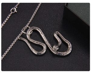 Dettaglio del ciondolo a serpente in argento con texture a scaglie su pelle nera
