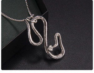 Vista macro di ciondolo a serpente in argento con trama a scaglie su scatola nera