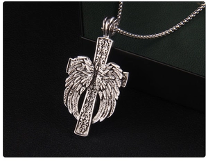 Détail macro d'un collier croix vintage argenté avec textures d'ailes et de plumes