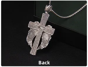 Détail du dos du pendentif croix argenté avec logo VORA et surface métallique texturée