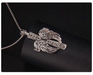 Vue macro détaillée du pendentif croix argent vintage avec plumes d'ailes d'ange