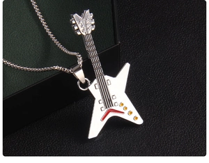 Macro detail of silver guitar pendant with red and yellow enamel on a black jewelry box