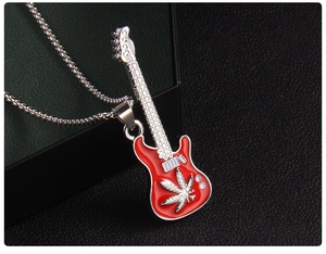 Détail d'un pendentif guitare en émail rouge avec motifs de feuilles sur fond de cuir noir