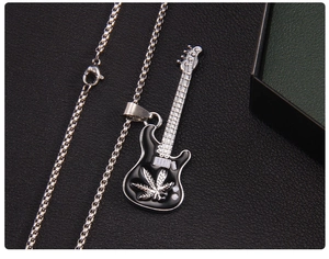Macro d'un collier pendentif guitare avec motif de feuille noire et chaîne box