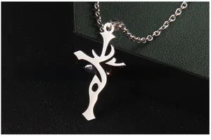 Gros plan d'un pendentif croix asymétrique argenté avec sa chaîne à maillons métalliques