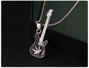 Détail macro du pendentif guitare argenté avec emblème de feuille sur boîte en cuir