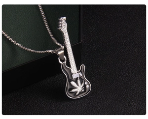 Détail d'un pendentif guitare en émail noir avec motifs de feuilles argentées