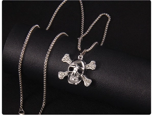 Close-up of skeleton pendant with rhinestones and guitar crossbones on a long chain