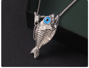 Vue macro du pendentif arête de poisson argenté avec œil bleu sur fond sombre