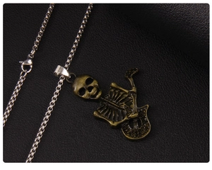 Close-up of retro skeleton guitar pendant with vintage bronze finish and silver square chain
