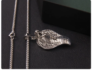 Macro detail of vintage cobra pendant with realistic silver scales on black leather surface