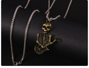 Detail of vintage punk skull guitar pendant on silver box chain over black leather