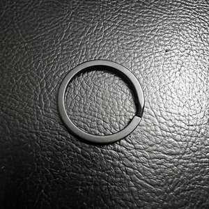 Matte black stainless steel motorcycle bell hanger keychain ring on leather background