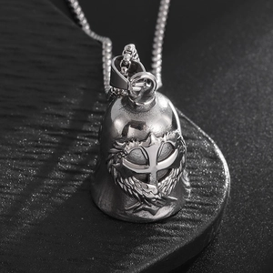 Macro detail of stainless steel guardian bell with wing and cross relief on box chain