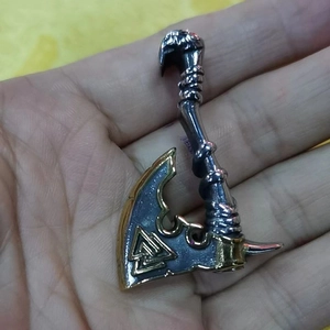 Close-up of a Viking axe pendant with golden edges and Nordic Valknut symbol