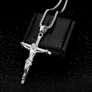 Macro view of silver cross pendant with Jesus relief and stainless steel box chain