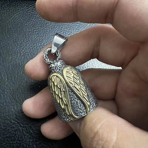 Détail d'une cloche d'ange vintage avec finition en acier texturé et ailes dorées