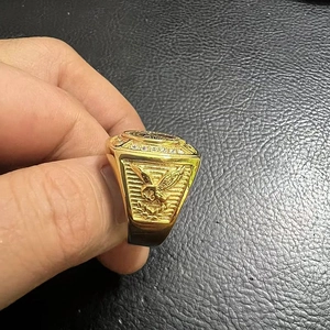 Macro detail of men's gold-plated eagle ring with sparkling zircon halo on black leather