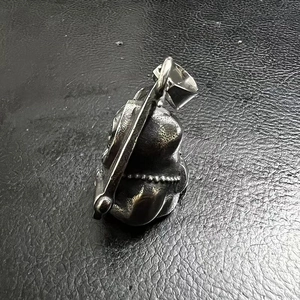 Macro shot of retro polished stainless steel grim reaper pendant on black leather